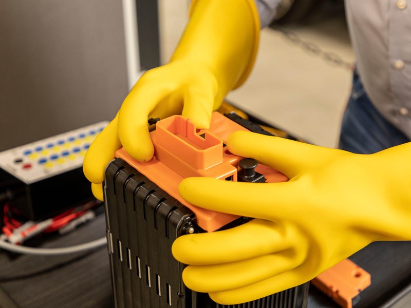 Elektroauto-Batterie mit Schutzhandschuhen anfassen